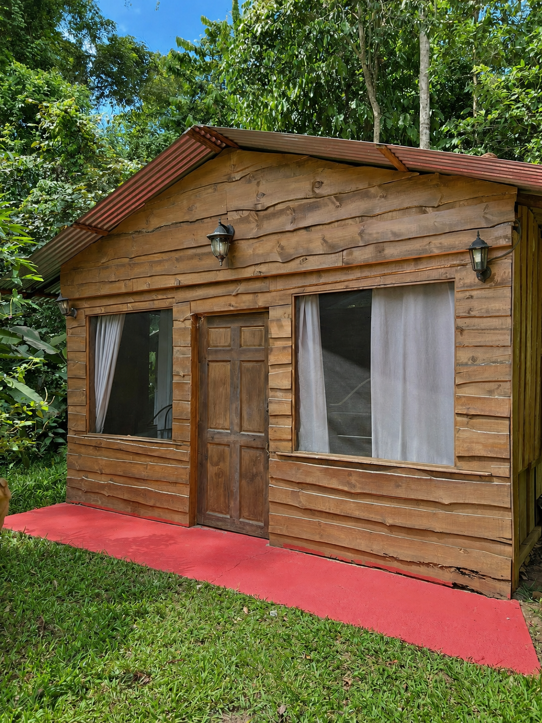 Otra cabaña de madera con dos ventanas y sendero exterior
